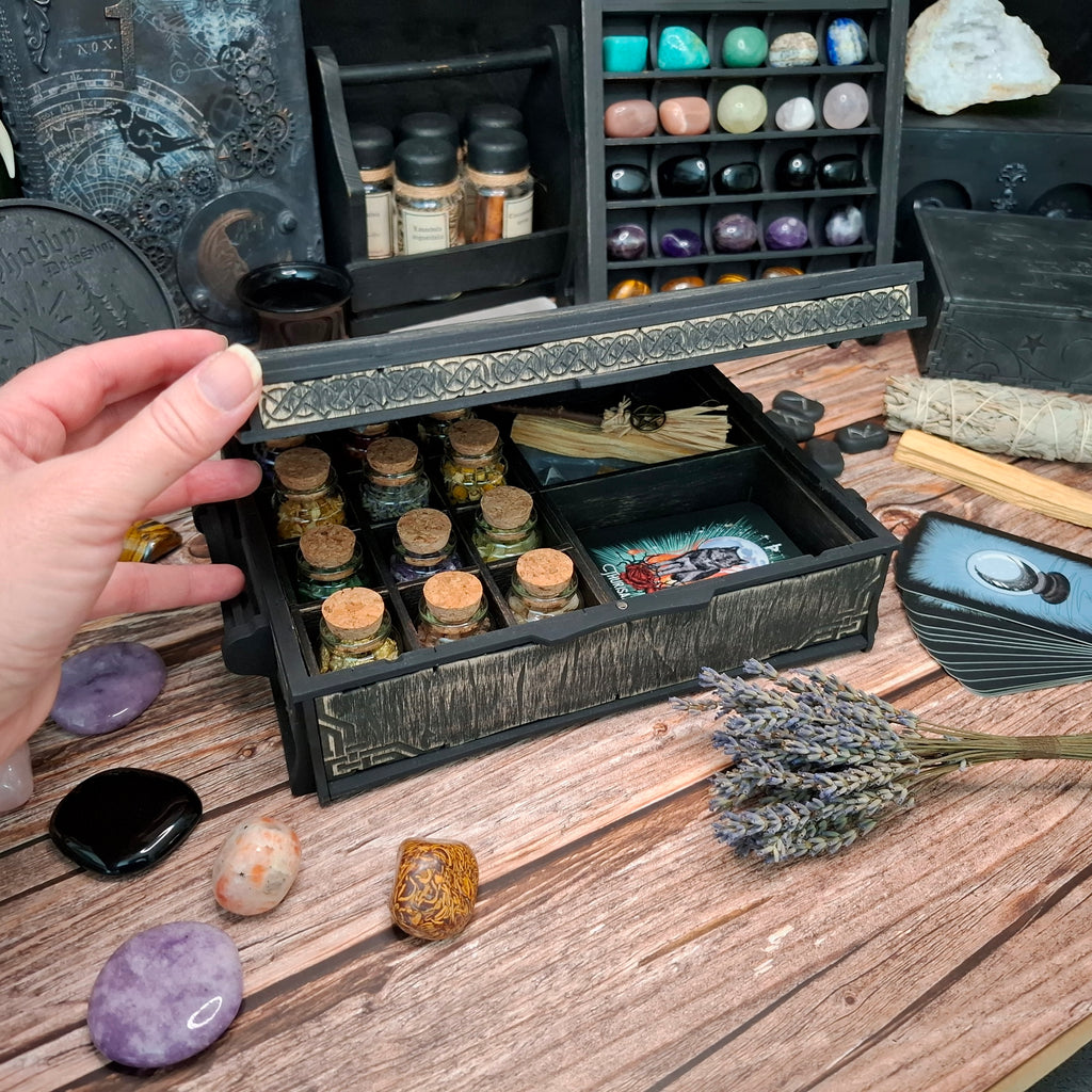 The Celtic ritual storage box in everyday use, keeping crystals, herbs, small bottles, incense, and tarot cards beautifully organized and within easy reach.

