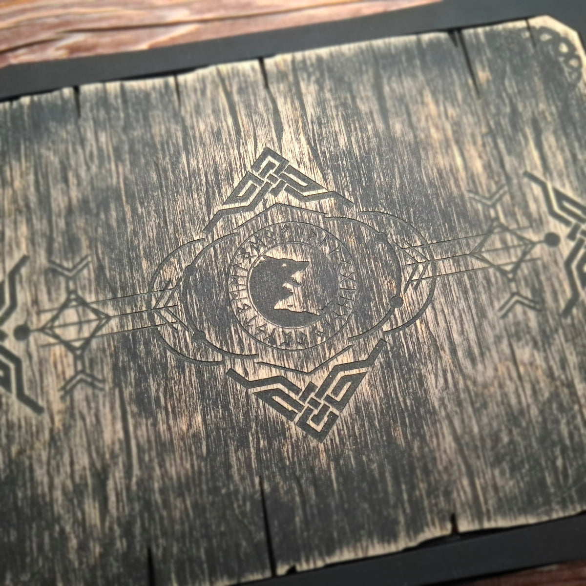 Close-up of the engraved wolf motif surrounded by runes and Celtic knotwork on the lid of a handcrafted Celtic ritual storage box.
