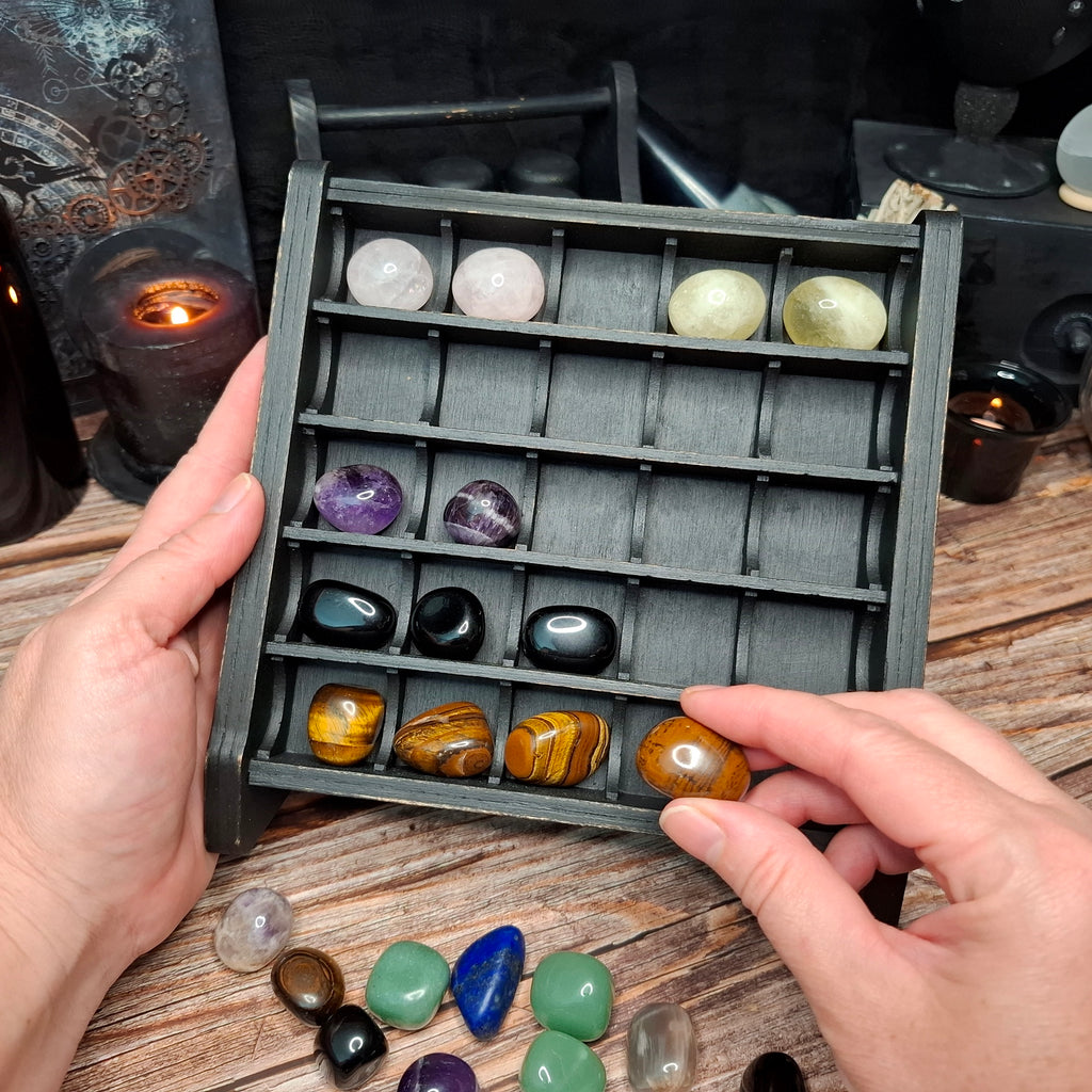 Wooden crystal storage shelf displaying a collection of tumbled crystals and gemstones.
