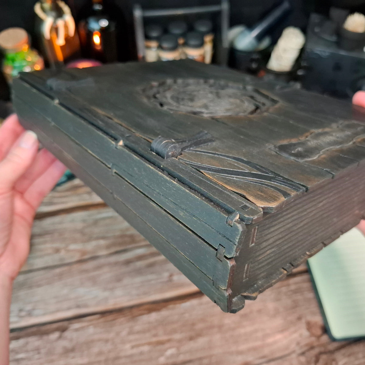 Detailed side view of the layered wooden spine construction of the raven grimoire box