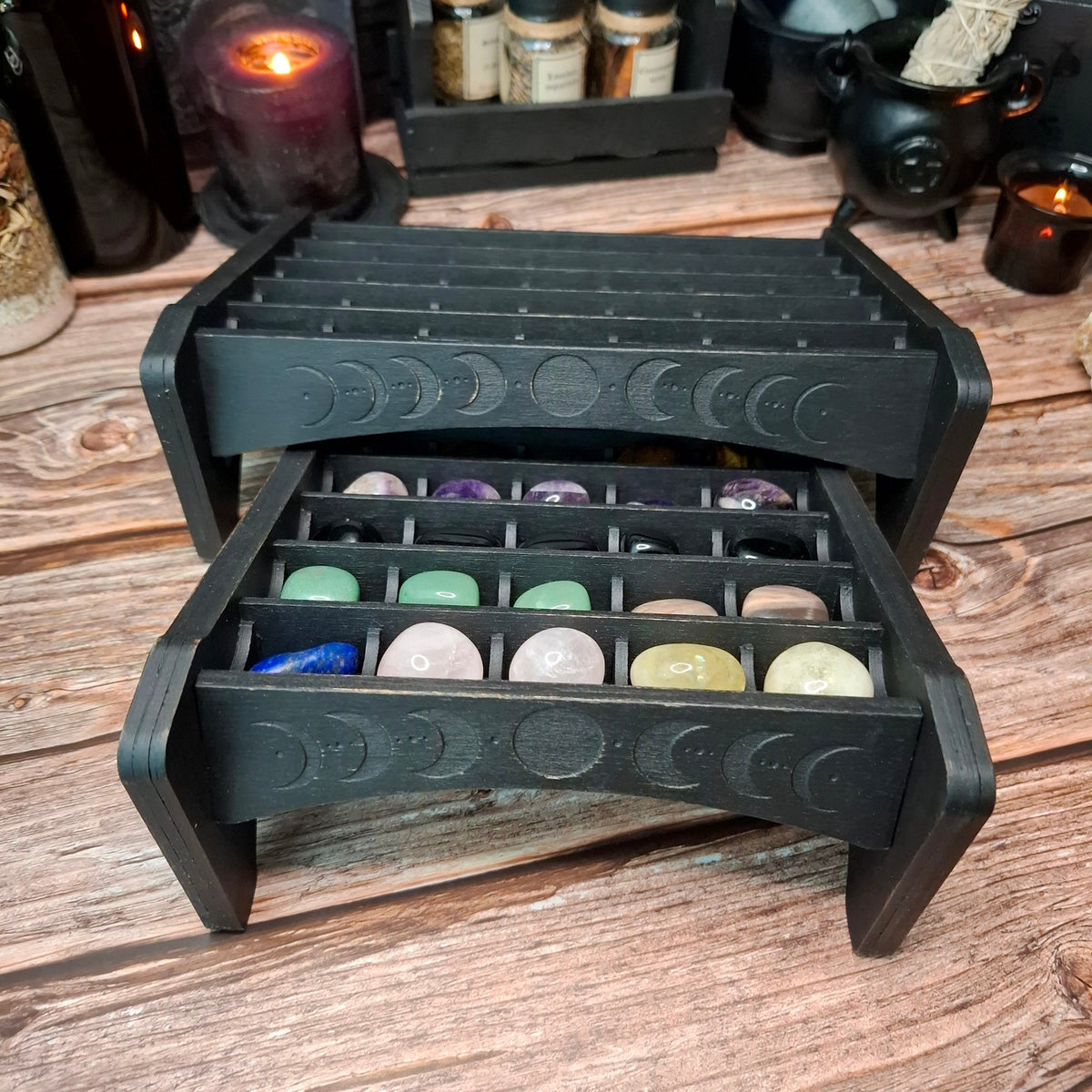 Open wooden crystal storage shelf with engraved moon phase design and crystal compartments.
