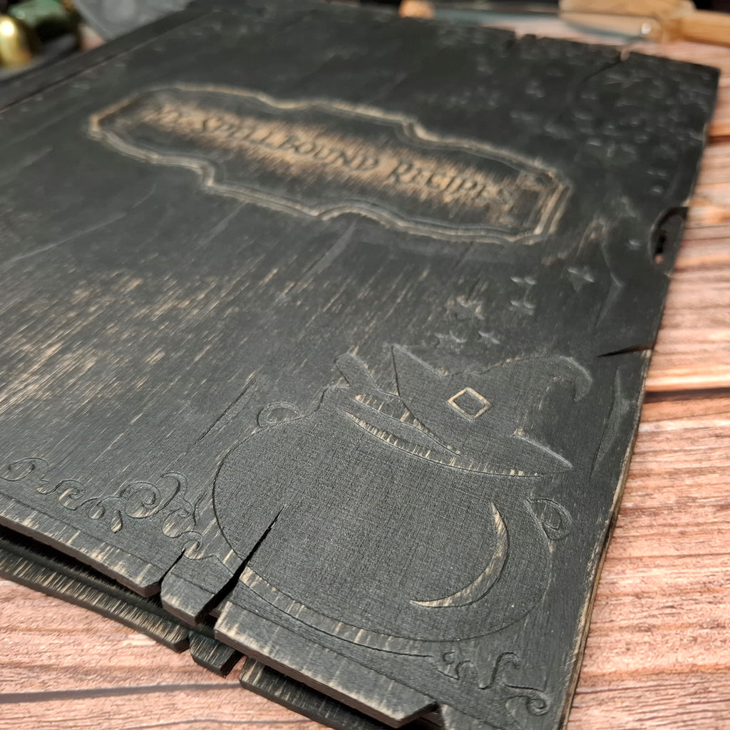 Engraved cauldron detail on a handmade witch-inspired recipe binder