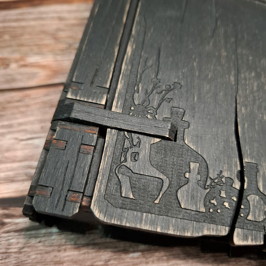 Decorative corner and cauldron engraving detail on a handmade wooden recipe binder