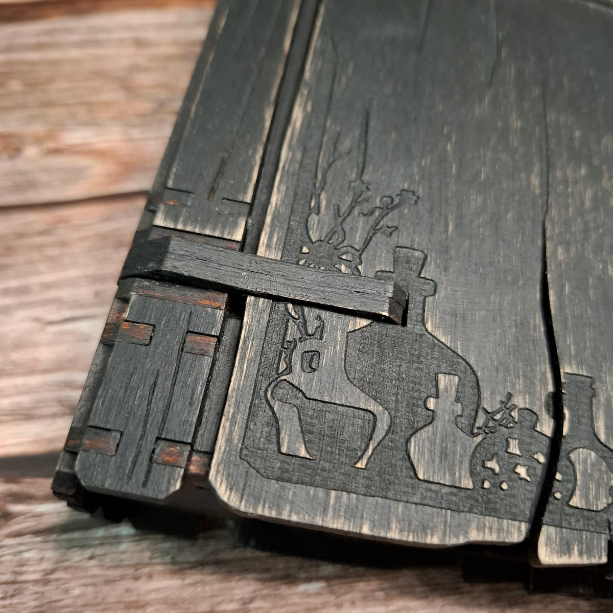 Decorative corner and cauldron engraving detail on a handmade wooden recipe binder