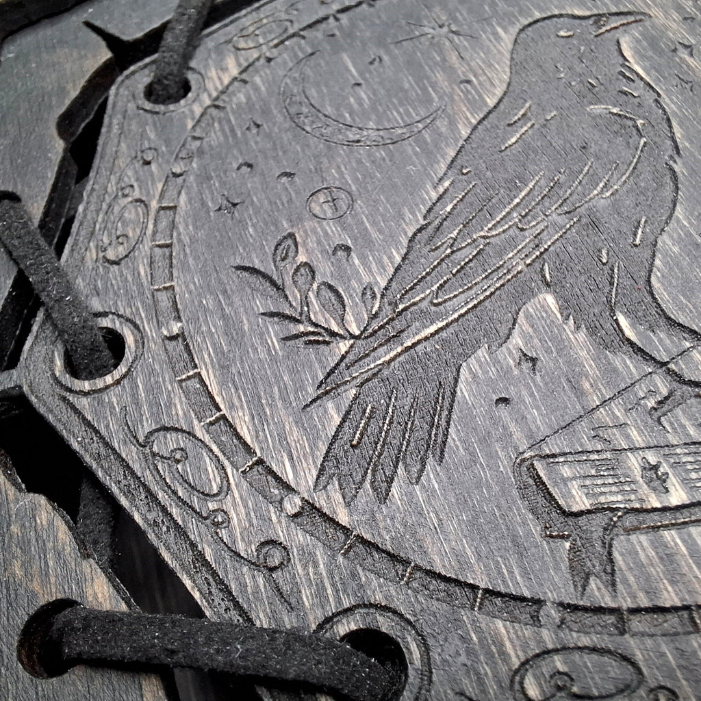Macro close-up of engraved raven artwork on wooden grimoire box